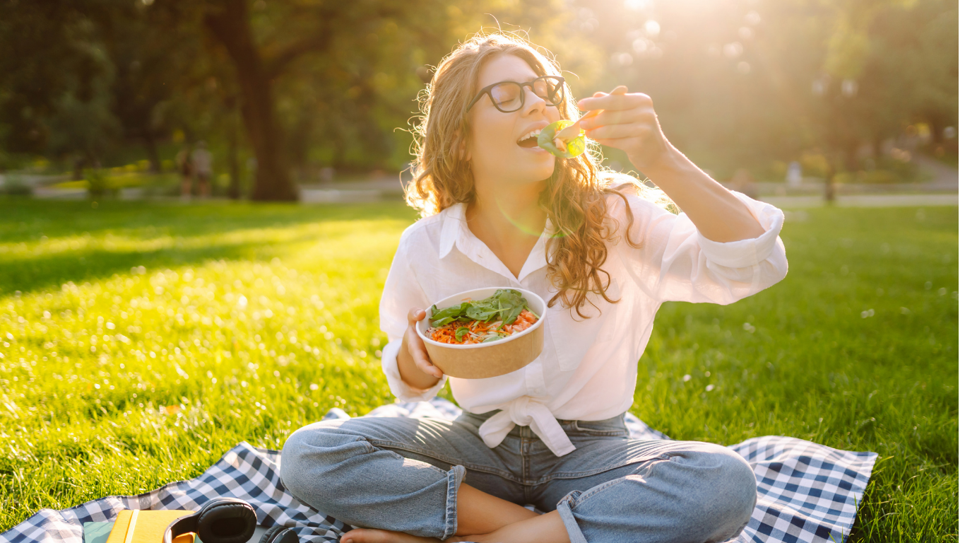 Women sitting on picnic blanket eating a salad